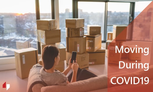 Woman on her phone surrounded by moving boxes.